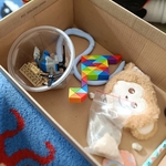 Kartonik z pamiątkami klocki LEGO w kubeczku_ kolorowa układanka_ maskotka małpki i woreczek z piaskiem..jpg