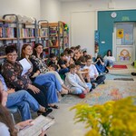 W bibliotece uczennica siedzi na fotelu i czyta. Naprzeciwko niej siedzą nauczyciele i uczniowie. (2).jpg