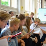 W bibliotece na pufach siedzą uczniowie. W tle telewizor z wyświetolną prezentacją..jpg