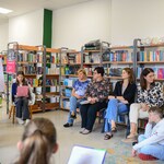 W bibliotece 2 uczennice siedzą na fotelach i czytają. Naprzeciwko niej siedzą nauczyciele i ucznowie..jpg