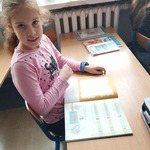 Uczennica siedząca w ławce uzupełnia zadania związane z Dniem Kropki.jpg