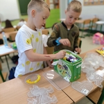 Dwóch chłopców wybiera kolorowe koraliki i układa je na przezroczystych podkładkach do tworzenia wzorów..jpg