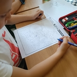 Chłopiec rozwiązuje zadanie typu połącz kropki na kartce_ siedząc przy szkolnej ławce..jpg