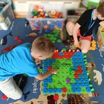 Dwóch chłopców buduje dużą konstrukcję z kółek Korbo na dywanie z mapą świata..jpg