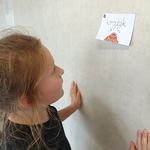Dziewczynka patrzy na kartkę z napisem krążek i rysunkiem kropki zawieszoną na ścianie..jpg