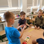 Chłopcy stoją przy stole i pracują nad budową konstrukcji z suchych makaronów spaghetti.jpg
