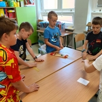 Grupa chłopców stoi przy stole i przygotowuje się do budowy konstrukcji z suchych spaghetti.jpg