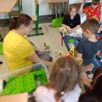 Dzieci i nauczycielka siedzą na podłodze w klasie i wspólnie bawią się kolorowymi klockami.jpg
