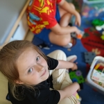 Dziewczynka siedzi na dywanie i patrzy w obiektyw_ obok niej chłopiec bawi się klockami..jpg