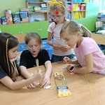 Grupa dziewczynek przy stole wspólnie buduje konstrukcję z makaronu spaghetti i taśmy.jpg