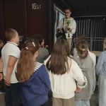 Przewodnik opowiada uczniom o wagonie stojącym w Muzeum Pamięci Sybiru.jpg