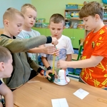 Grupa chłopców pracuje wspólnie nad budową konstrukcji z kubków_ gumek i sznurka.jpg