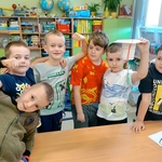 Grupa chłopców pozuje z dumą przy stole_ jeden z nich trzyma zbudowaną konstrukcję z kubka i sznurków..jpg