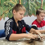 Dwaj chłopcy ugniatają glinę podczas warsztatów..jpg
