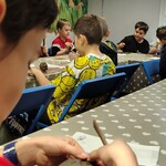 Chłopiec rzeźbi w glinie. W tle inne dzieci podczas warsztatów..jpg