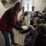 Przewodniczka muzealna podaje dzieciom świeżo wypieczone opłatki do spróbowania.jpg