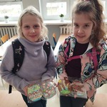 Dwie dziewczynki_ trzymając ozdobione przez siebie ciastka wielkanocne_ pozują do zdjęcia.jpg