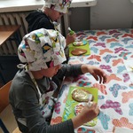 Dwoje chłopców przy stoliku dekoruje ciasteczka wielkanocne.jpg