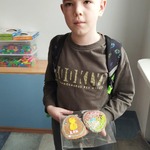 Uczeń trzyma w rękach udekorawane przez siebie ciasteczka wielkanocne w kształcie pisanek.jpg