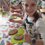Uśmiechnięta dziewczynka pozuje do zdjęcia w trakcie ozdabiania ciasteczka masą cukrową.jpg
