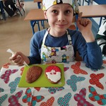 Uśmiechnięty chłopiec pozuje do zdjęcia podczas dekorowania ciastek wielkanocnych.jpg