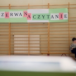 Uczeń siedzi na ławeczce w sali gimastycznej i czyta książkę..jpg