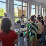 Na korytarzu szkolnym przy stołach  z książkami stoi grupa uczniów..jpg
