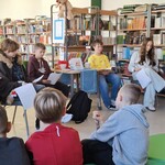 W bibliotece uczniowie klasy ósmej czytają książkę uczniom klasy drugiej..jpg
