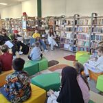 W bibliotece uczniowie klasy ósmej czytają książkę uczniom klasy trzeciej..jpg