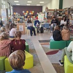 W bibliotece starsi uczniowie czytają książkę uczniom klasy drugiej..jpg