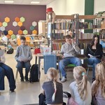 W bibliotece uczniowie ósmej klasy czytają książkę uczniom klasy drugiej..jpg