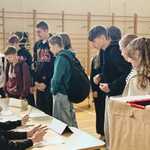 W sali stoi grupa uczniów_ przy stole siedzi uczeń..jpg