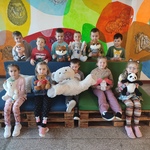 Grupa uśmiechniętych dzieci z pluszowymi zabawkami na tle kolorowej ściany..jpg
